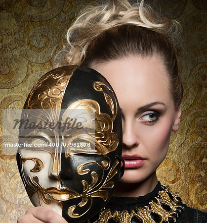close-up carnival portrait of very beautiful blonde woman with baroque mask in the hands and antique precious jewellery