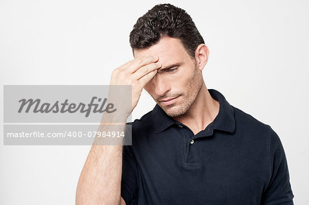 Confused young man holding hand to forehead
