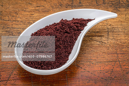 dried acai berry powder in a teardrop shaped bowl against rustic wood
