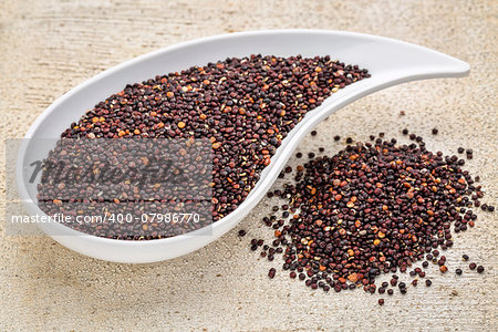 gluten free black quinoa grain grown iin Bolivia ,  a teardrop shaped bowl against white painted grunge wood