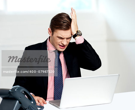 Unhappy businessperson looking at his laptop. Business loss