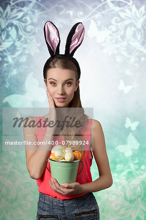 Pretty, easter girl with rabbit, fluffy ears and bucket of easter eggs. She wears to and jeans shorts. She has got nice make up.