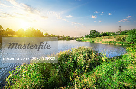 Bright sunset over calm river in summer