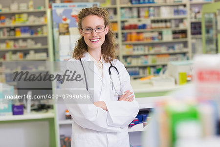 Phamacist in lab coat with stethoscope and arms crossed in the pharmacy