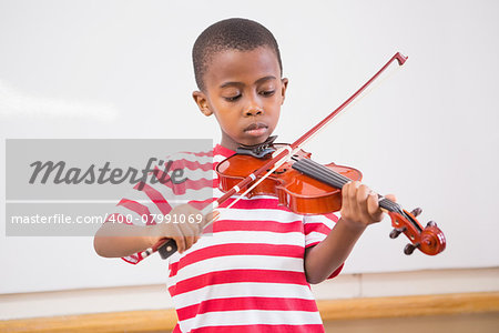 Focus pupil playing violin in classroom at elementary school
