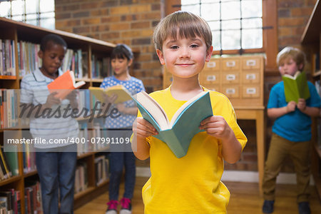 Cute pupils reading books at library at elementary school