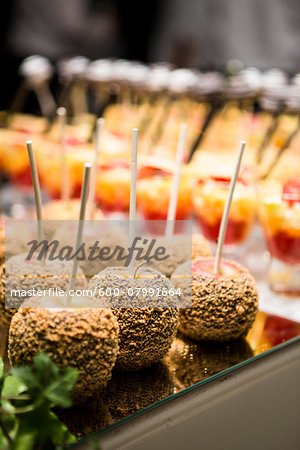 Close-up of Chocolate and Nut Covered Apples and Glasses of Fruit Cocktail on Dessert Table