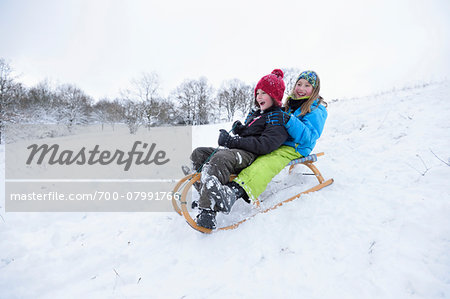 Close-up of two girls playing in the snow with sled, winter, Bavaria, Germany