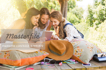 Three teenage girls using digital tablet in tree house