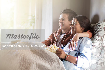Teenage couple lying in bed and watching tv