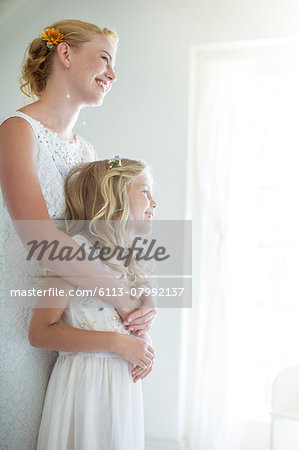 Bride embracing bridesmaid and looking out of window