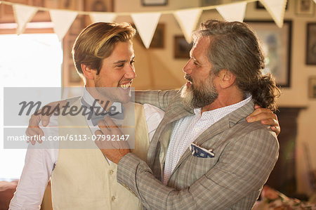 Best man and bridegroom standing and embracing in domestic room