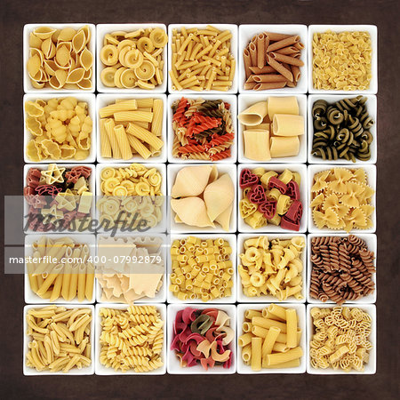 Large pasta dried food sampler in square dishes over brown lokta paper background.