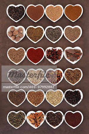 Large spice selection in heart shaped dishes over lokta paper background.