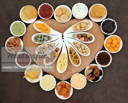 Savoury snack and dip party food selection in porcelain dishes  on a heart shaped wooden board.