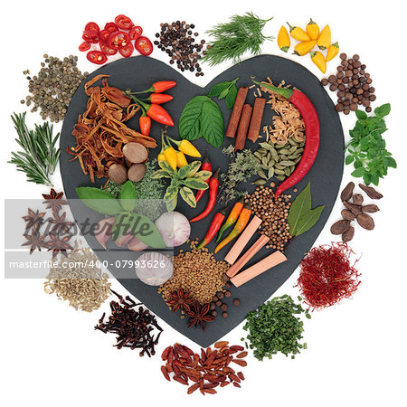 Herb and spice selection on heart shaped slate over white background.