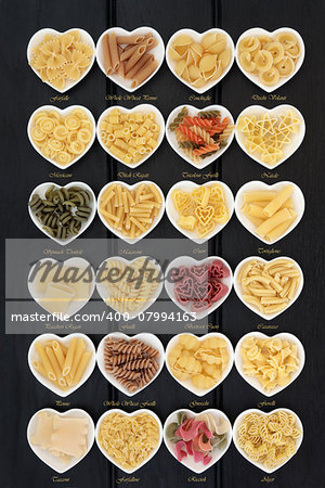 Large pasta food selection in heart shaped porcelain dishes over dark wood background. Titles provided.