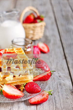 Homemade belgian waffles with ripe strawberry, honey and milk on wooden background