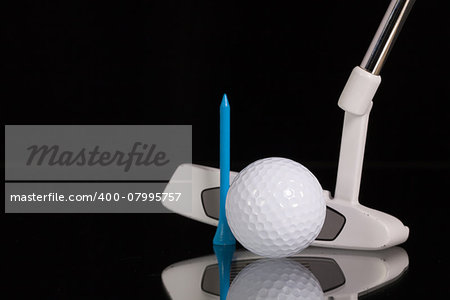 Golf putter and different golf equipments on the black glass desk
