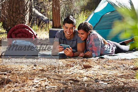Young camping couple looking at smartphone in forest, Los Angeles, California, USA