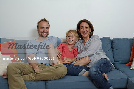 Parents with son sitting on sofa