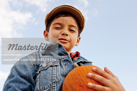 Low angle portrait of boy holding pumpkin
