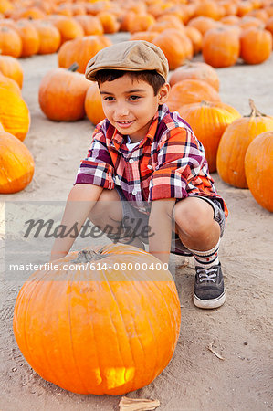 Portrait of boy choosing pumpkin in farmyard