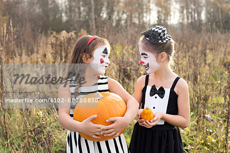 Girls with painted faces holding pumpkins