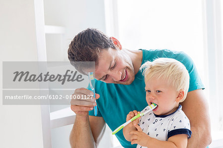 Father and son brushing teeth together