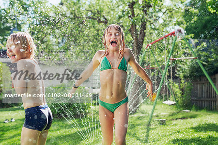 Girl and boy playing with water in garden