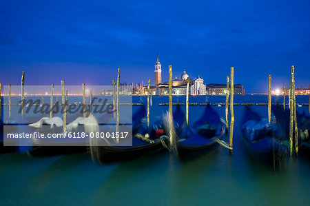 A view from the Riva degli Schiavoni and the Piazza San Marco across the water to the island and church of San Giorgio Maggiore. Gondolas moored at dusk.