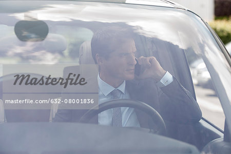 Businessman talking on cell phone in car