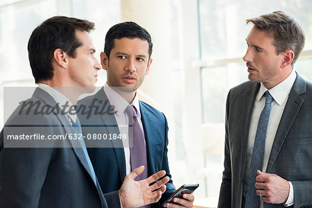 Businessmen standing together having serious discussion Businessmen standing together having serious discussion