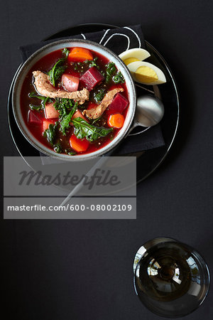 Beet and Kale soup servied with a boiled egg on a black plate, studio shot on black background