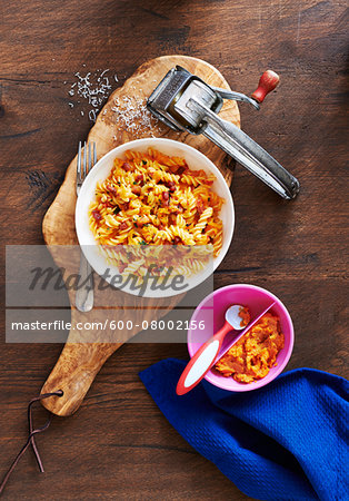 Rotini Pasta with sweet potato sauce on a wooden cutting board with cheese grater, studio shot