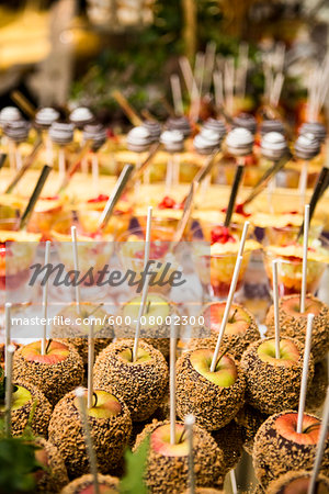 Close-up of Chocolate and Nut Covered Apples and Glasses of Fruit Cocktail on Dessert Table