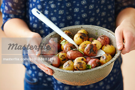 Close-up of Woman's Hands Holding Bowl of Grilled Red and White Baby Potatoes