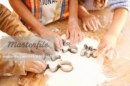 Children cutting shapes into dough in kitchen