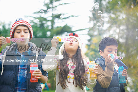 Siblings blowing bubbles in garden