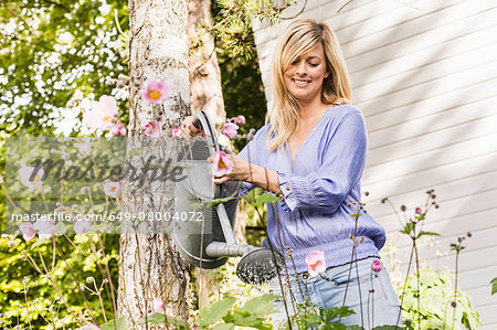 Mid adult woman watering flowers in garden