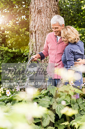 Husband and wife watering plants in garden