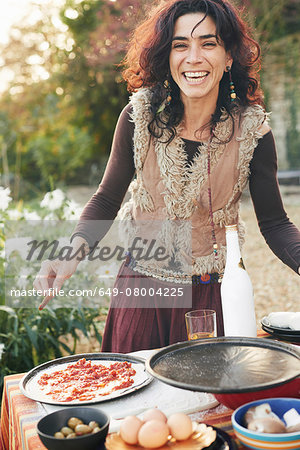 Portrait of mature hippy female preparing pizza in garden Portrait of mature hippy female preparing pizza in garden