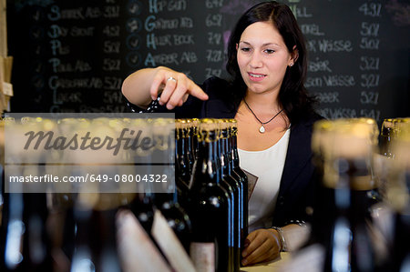 Woman counting bottles of wine in shop