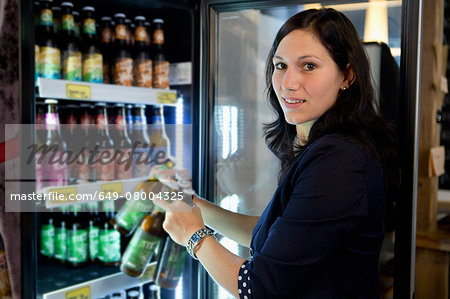 Woman filling fridge with drinks bottles in shop