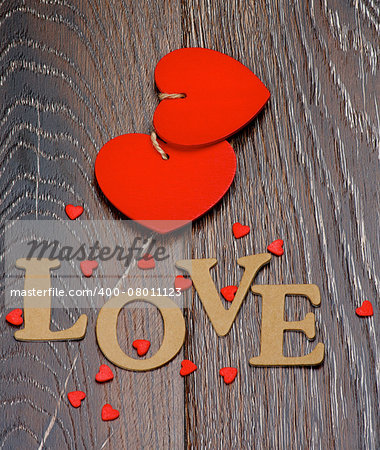 Two Red Hearts and Cardboard Word Love closeup on Dark Wooden background