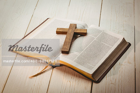 Open bible and wooden cross on wooden table