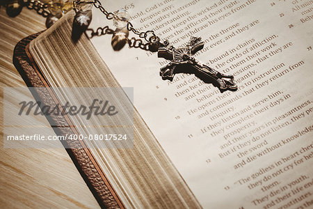 Open bible and silver crucifix on wooden table