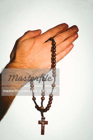 Hand holding wooden rosary beads on white background
