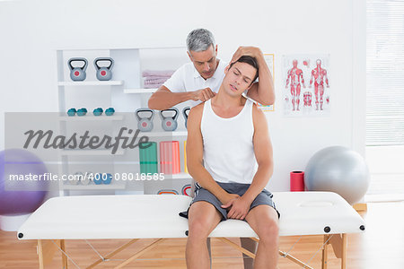 Doctor examining his patient neck in medical office