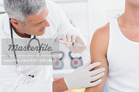 Doctor doing an injection to his patient in medical office